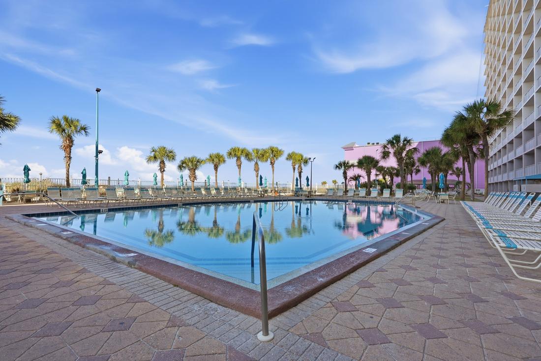 Summit’s outdoor swimming pool with palm trees and the beach beyond
